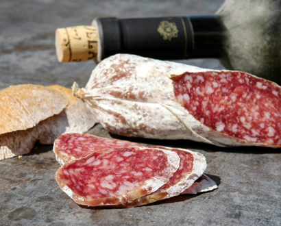 Saucisson artisanal accompagné d'une bouteille de vin rouge, une combinaison classique.